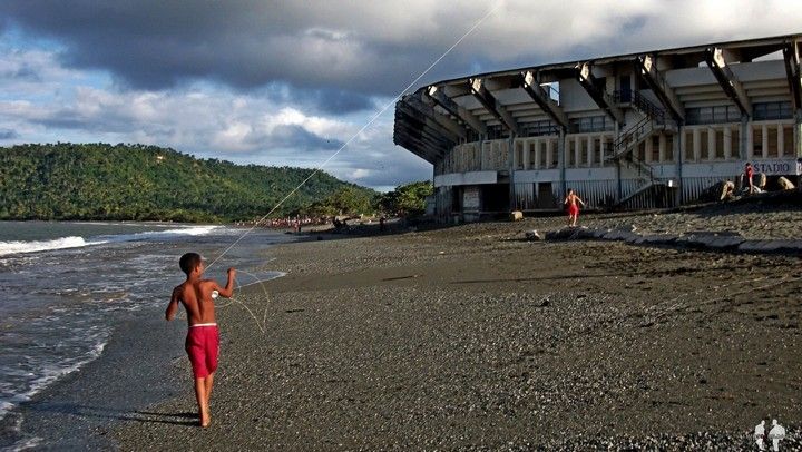 Estadio de Pelota y niños jugando en playa negra de Baracoa